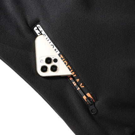 Bolsillo con cierre del conjunto negro forrado para hombre, mostrando capacidad para guardar un celular moderno.