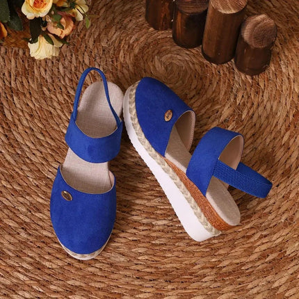 Sandalia azul de mujer con cuña, hebilla ajustable y punta cerrada, estilo casual moderno, verano urbano.