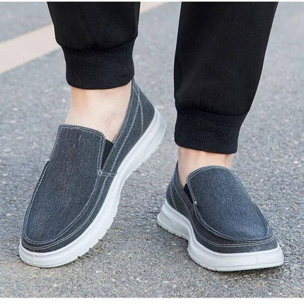 Zapatos de lona casuales gris oscuro para hombres, ideales para caminar, con suela blanca y diseño slip-on cómodo.